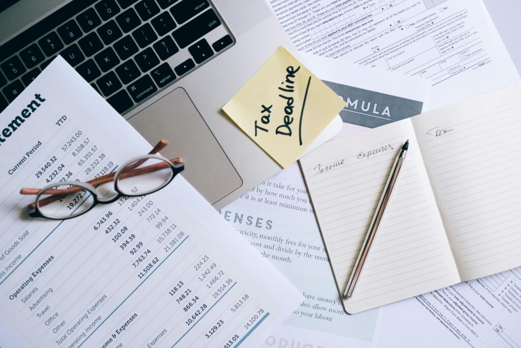 A notebook and pen near the laptop and documents on the table