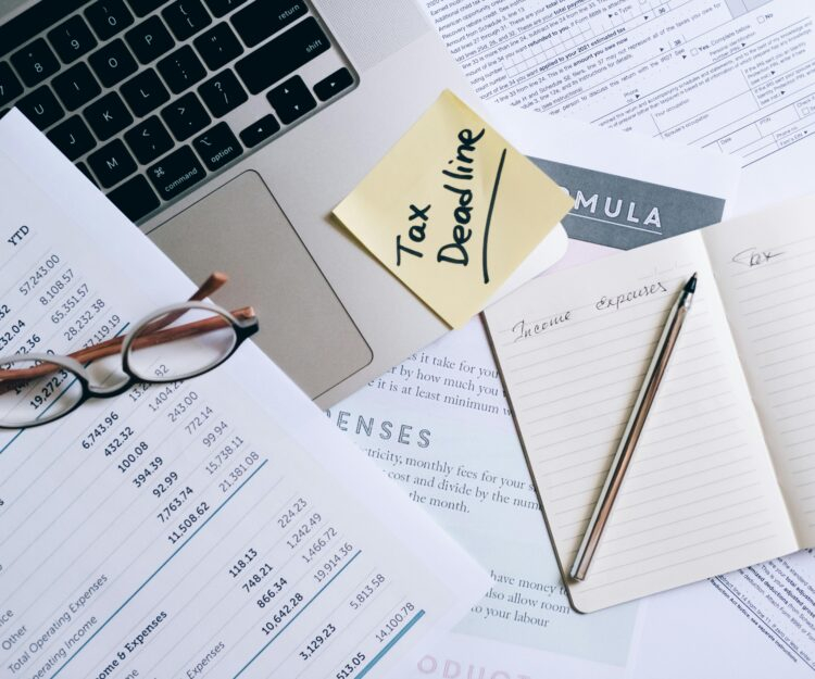 A notebook and pen near the laptop and documents on the table