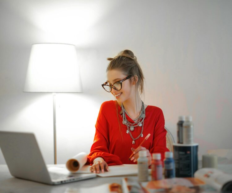 Woman in red long sleeve shirt looking at her laptop